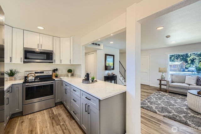 kitchen featuring stainless steel appliances, white cabinetry, gray cabinets, and light wood-type flooring