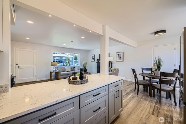 kitchen featuring light stone counters, gray cabinets, and light hardwood / wood-style flooring