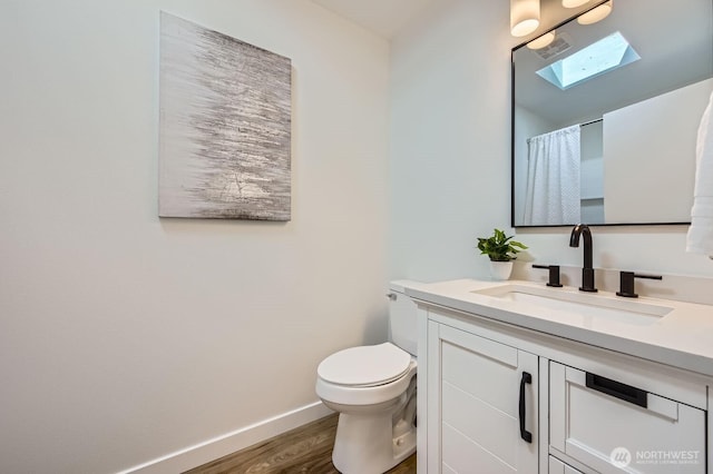 bathroom featuring vanity, a skylight, toilet, and wood-type flooring