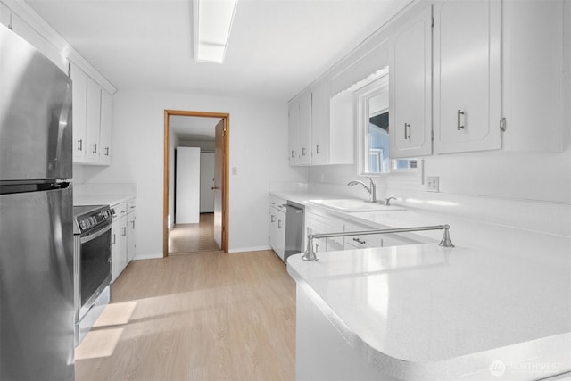 kitchen with appliances with stainless steel finishes, kitchen peninsula, sink, and white cabinets