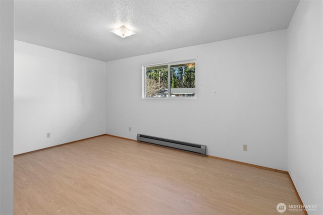 empty room with a baseboard heating unit, a textured ceiling, and light hardwood / wood-style flooring