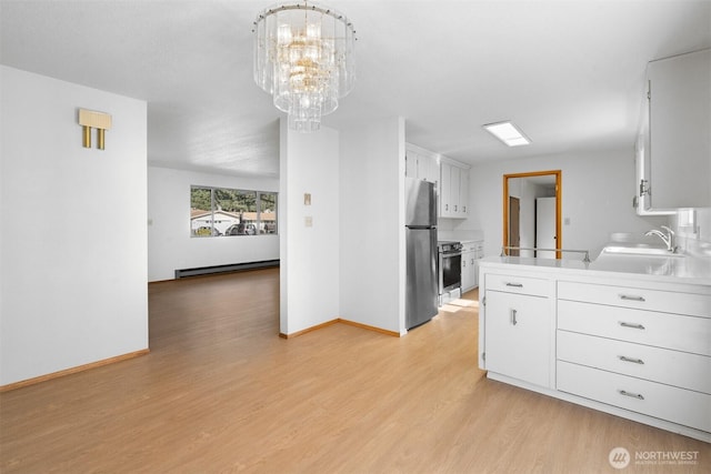 kitchen featuring sink, baseboard heating, white cabinetry, stainless steel appliances, and a chandelier