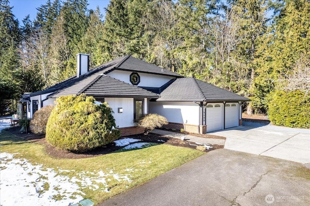 view of front of property featuring brick siding, a chimney, concrete driveway, an attached garage, and a front yard