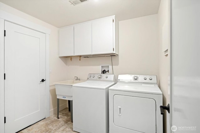 clothes washing area featuring a sink, cabinet space, visible vents, and washer and dryer