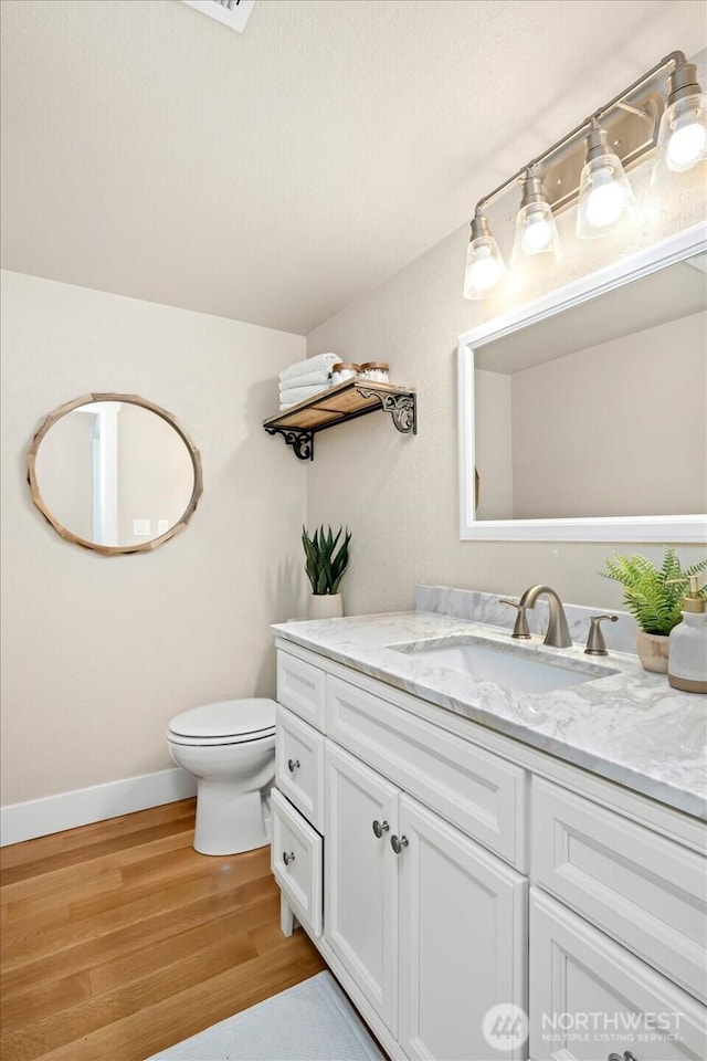 bathroom featuring baseboards, vanity, toilet, and wood finished floors