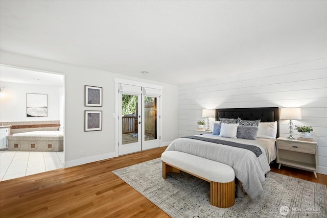 bedroom featuring access to outside, baseboards, ensuite bathroom, and wood finished floors