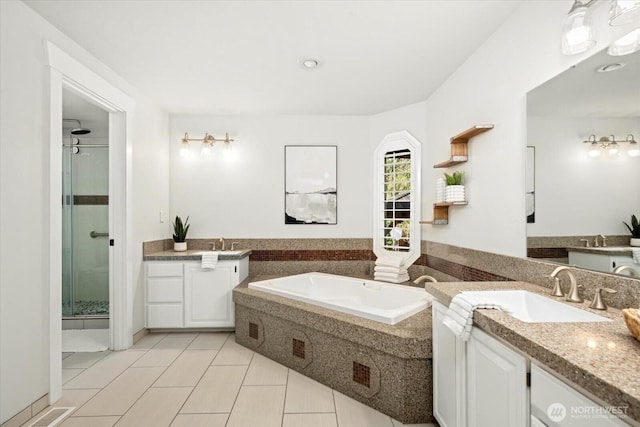 bathroom with a stall shower, visible vents, two vanities, a sink, and a bath