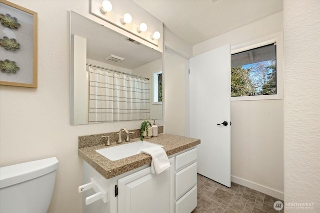 full bath featuring a wealth of natural light, visible vents, vanity, and toilet