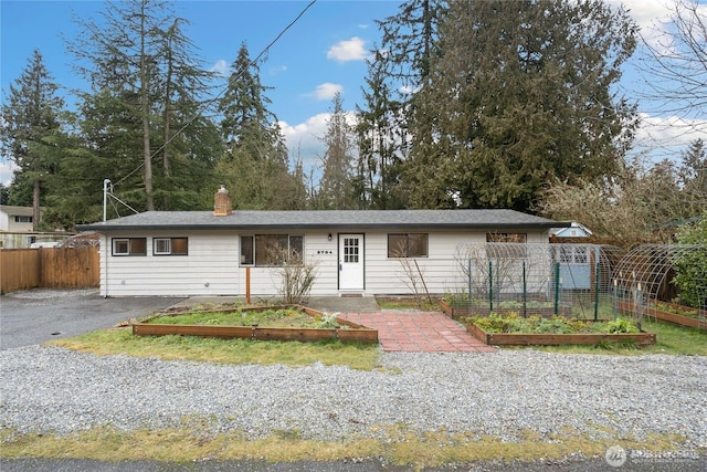 ranch-style home with a garden, fence, and a chimney