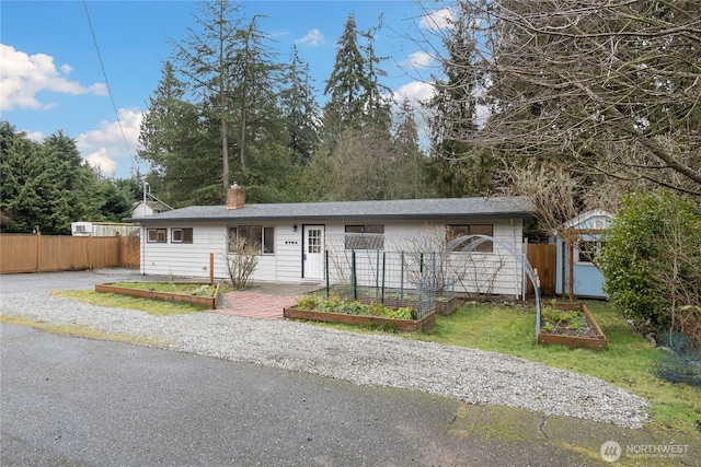 ranch-style house with an outbuilding, fence, a garden, a storage unit, and a chimney