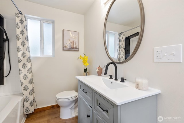 full bath with toilet, shower / tub combo, wood finished floors, vanity, and baseboards