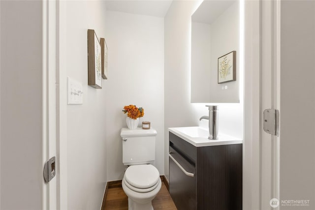 bathroom with baseboards, vanity, toilet, and wood finished floors