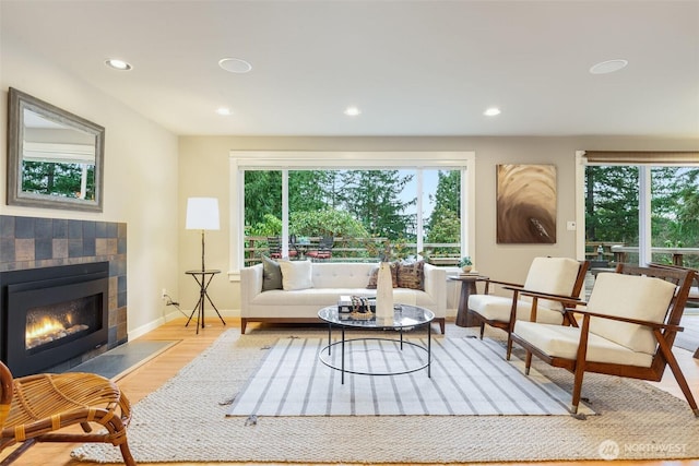 interior space with recessed lighting, baseboards, a tiled fireplace, and wood finished floors