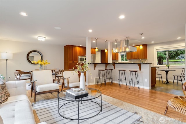 living area featuring baseboards, light wood-style flooring, and recessed lighting