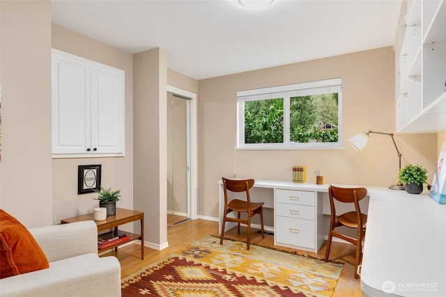 office area featuring light wood-style floors, built in study area, and baseboards