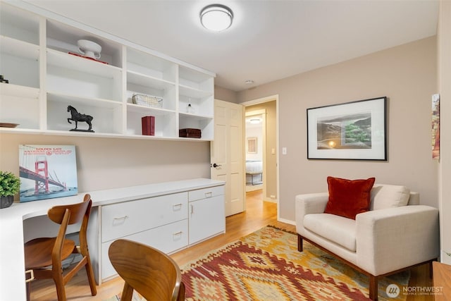 living area featuring baseboards, built in study area, and light wood-style floors