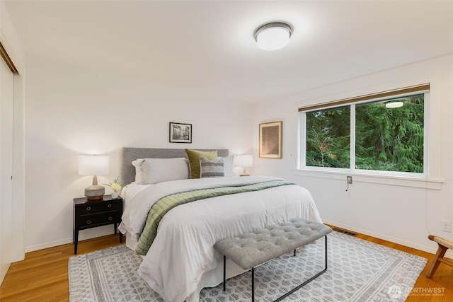 bedroom with light wood finished floors, a closet, and baseboards