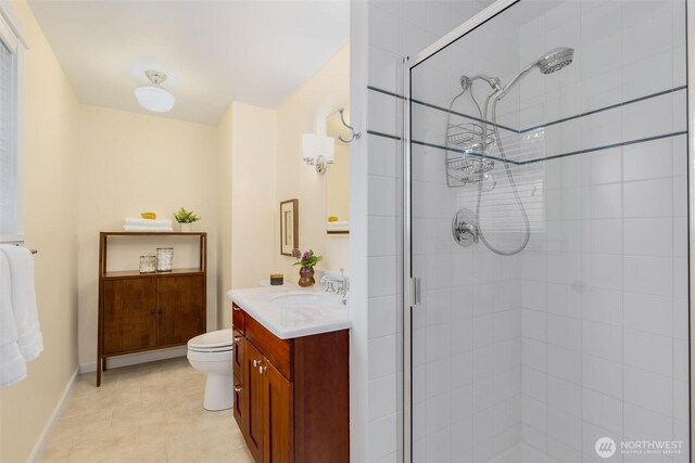 full bath with toilet, a stall shower, baseboards, and vanity