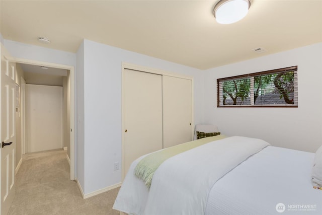 bedroom featuring light carpet, visible vents, baseboards, and a closet