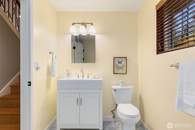 half bath with marble finish floor, vanity, toilet, and baseboards