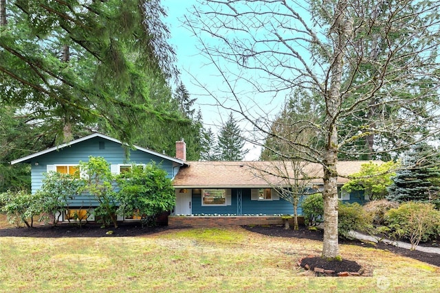 tri-level home with a shingled roof, a chimney, and a front yard