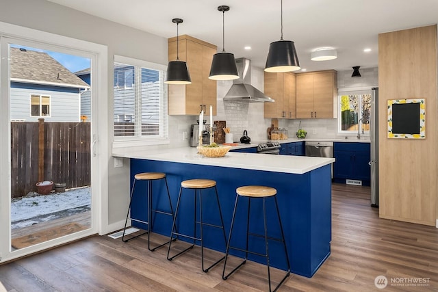 kitchen with extractor fan, a breakfast bar area, hanging light fixtures, and light brown cabinets