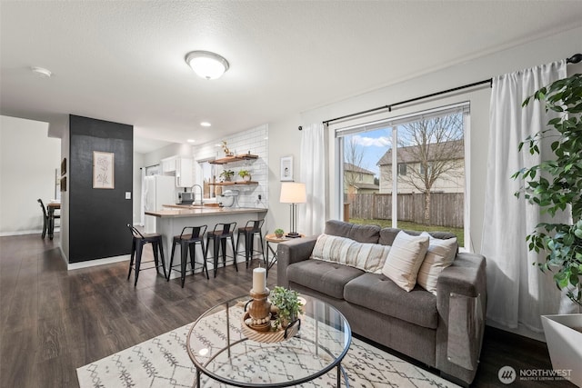 living room featuring a textured ceiling, baseboards, and dark wood-style flooring