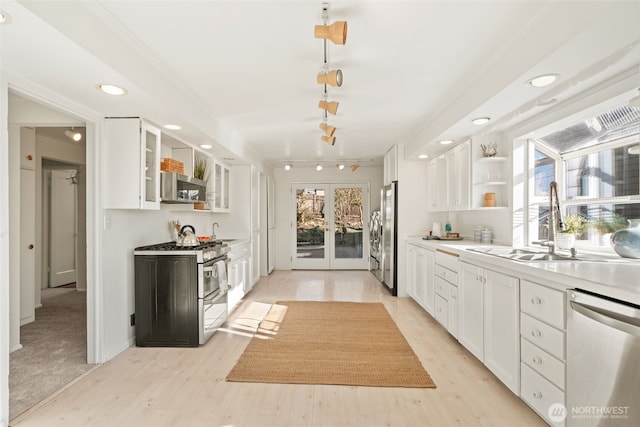 kitchen featuring french doors, sink, white cabinetry, light wood-type flooring, and stainless steel appliances