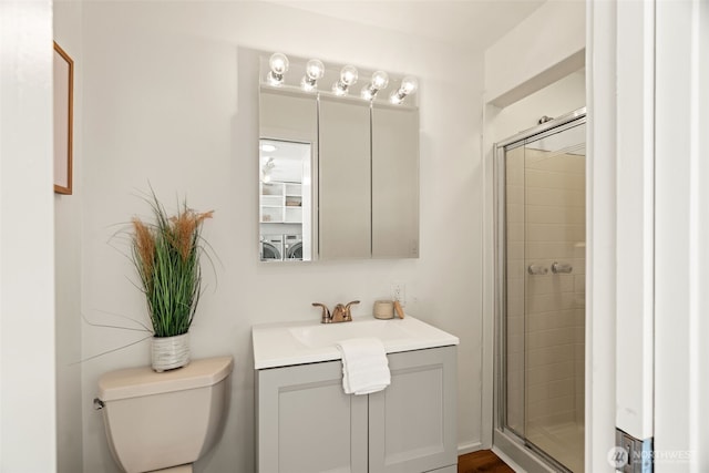 bathroom with vanity, toilet, a shower with shower door, and washer / dryer