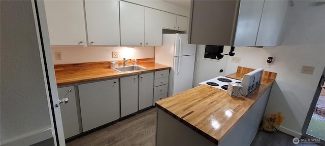 kitchen with dark wood-style flooring, wood counters, white cabinetry, freestanding refrigerator, and a sink
