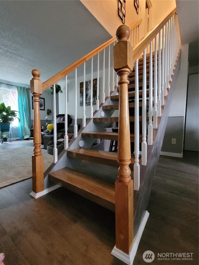 stairway with a textured ceiling and wood finished floors
