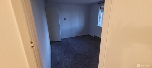 unfurnished room with a baseboard radiator and dark colored carpet