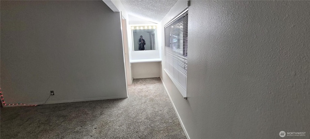 hall featuring a textured ceiling, carpet floors, lofted ceiling, a textured wall, and baseboards