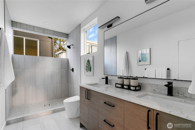 bathroom featuring vanity, tiled shower, tile patterned floors, and toilet