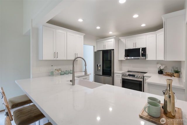 kitchen with sink, stainless steel appliances, white cabinetry, and kitchen peninsula