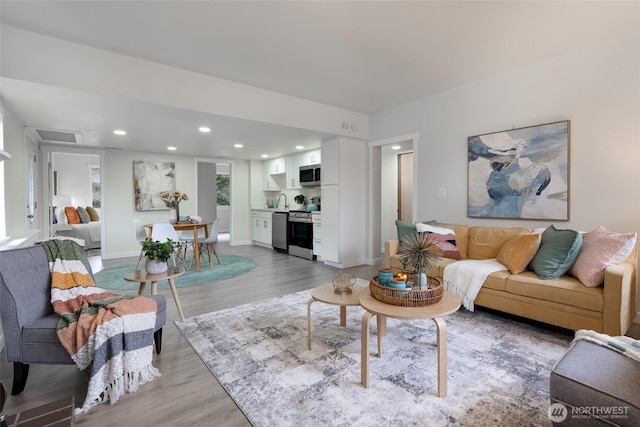 living room with light hardwood / wood-style flooring and sink