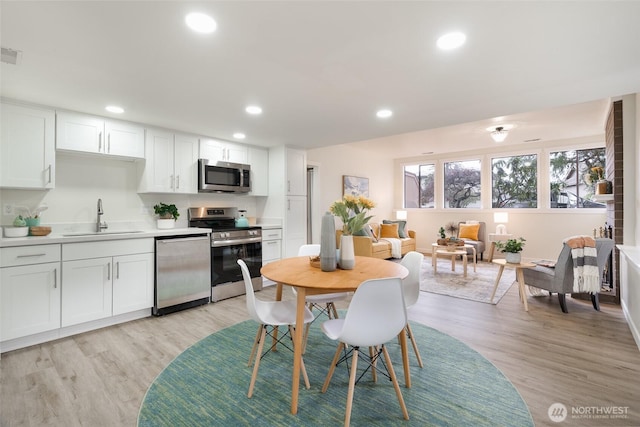 kitchen featuring white cabinetry, stainless steel appliances, light hardwood / wood-style flooring, and sink