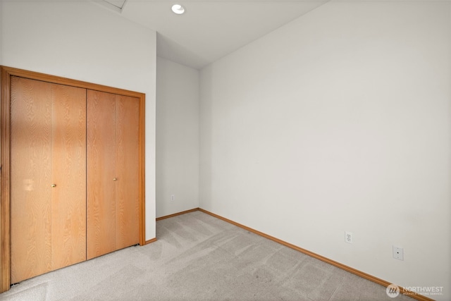 unfurnished bedroom with light carpet and a closet