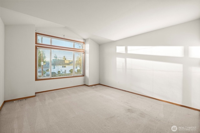 carpeted empty room featuring vaulted ceiling