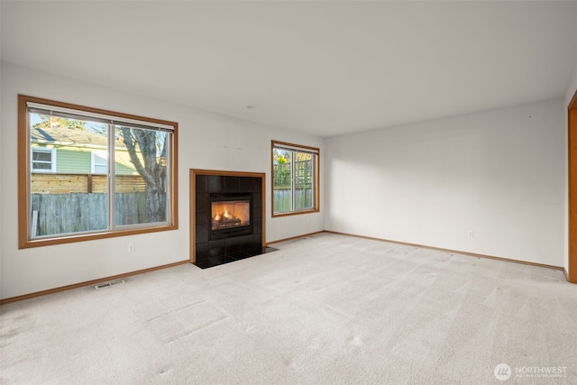 unfurnished living room featuring plenty of natural light, a fireplace, and light carpet