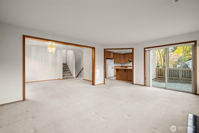 unfurnished living room with an inviting chandelier and light carpet