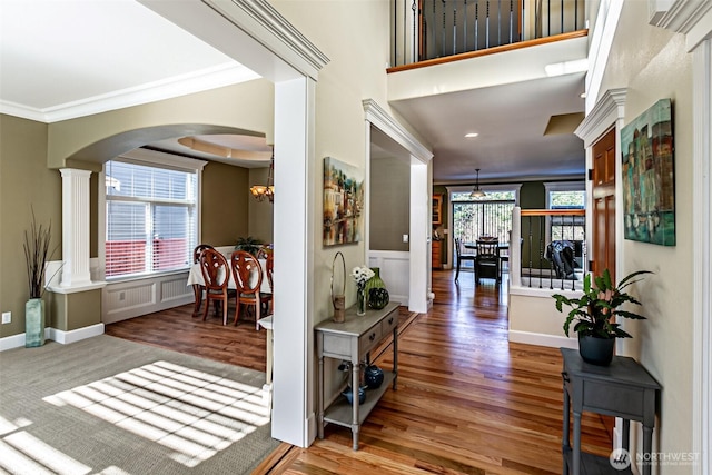 foyer entrance with decorative columns, crown molding, hardwood / wood-style floors, and a notable chandelier