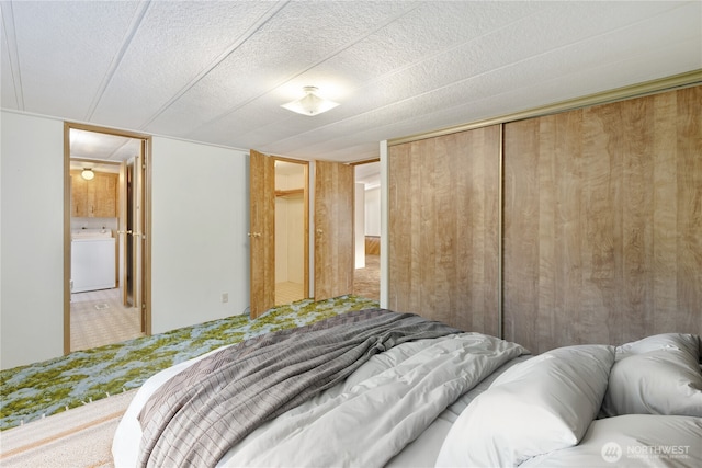 carpeted bedroom featuring washer / clothes dryer and a closet