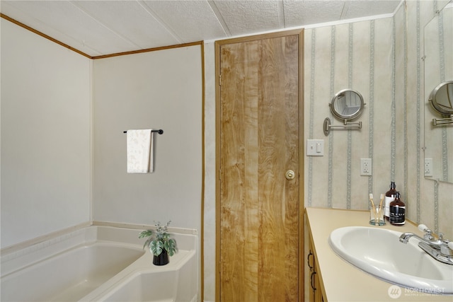 bathroom featuring a bathing tub, vanity, and a textured ceiling