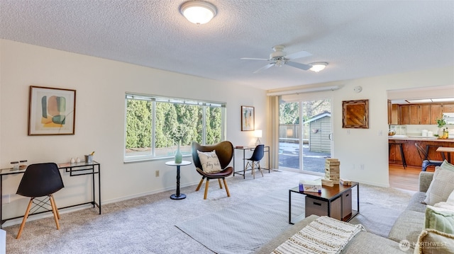 carpeted living room featuring ceiling fan and a textured ceiling