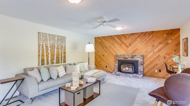 carpeted living room with ceiling fan, a textured ceiling, and wood walls