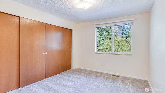 unfurnished bedroom featuring carpet flooring, a closet, and a textured ceiling