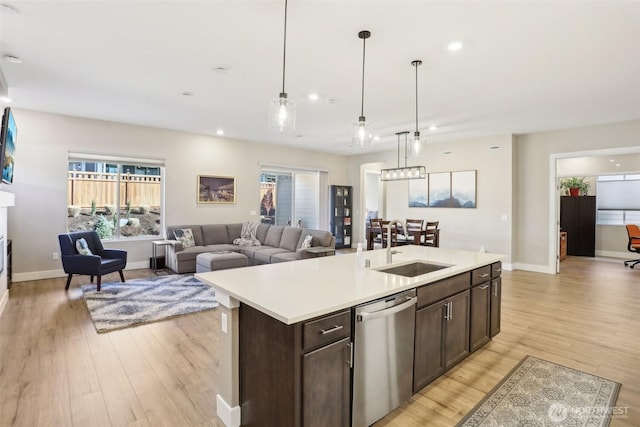 kitchen featuring sink, dark brown cabinets, dishwasher, an island with sink, and pendant lighting