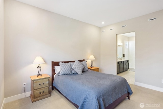 bedroom featuring ensuite bathroom and light carpet