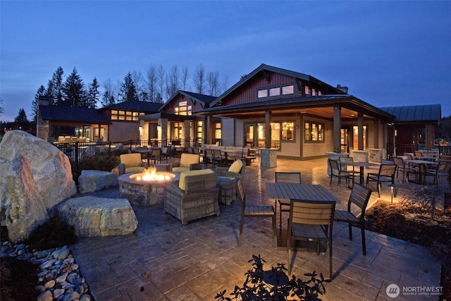 back house at dusk featuring a patio area and an outdoor fire pit